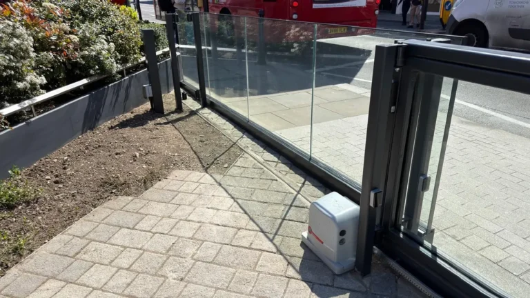 An automated glass sliding gate on a commercial forecourt in London