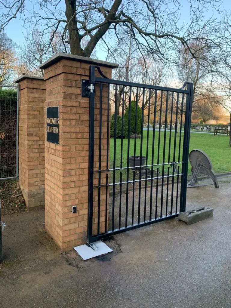 Black estate gates at a brick-piered cemetery entrance