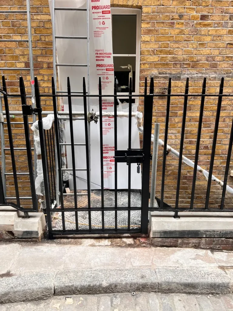 A black pedestrian gate on a cobbled London street