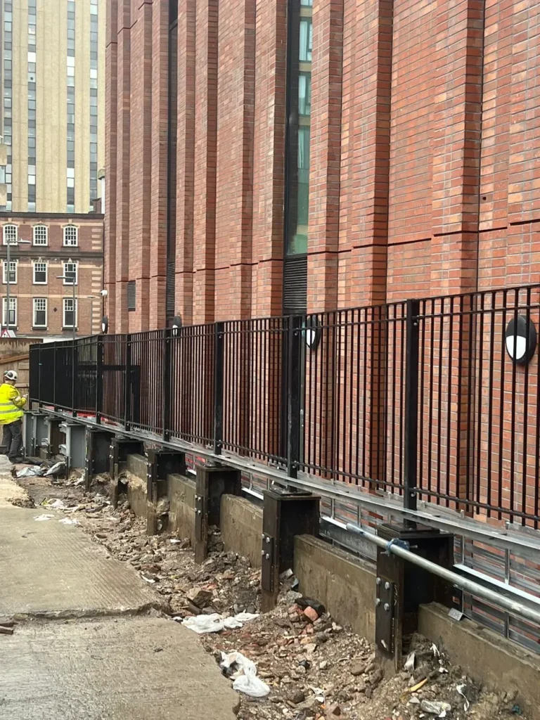 Black railings along the base of a red-brick building