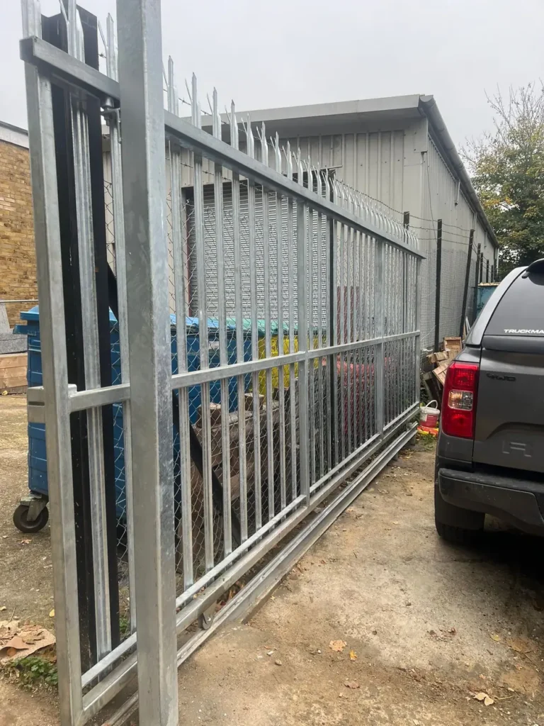 A galvanised palisade sliding gate with a vehicle at a yard entrance