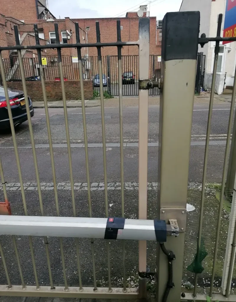 A linear gate automation actuator installed on a metal gate on a residential street