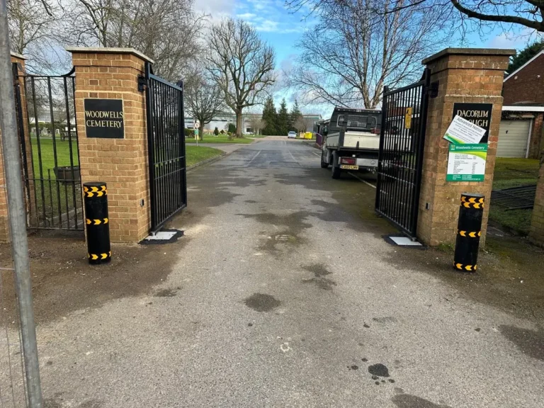 A protective bollard beside estate gates at a site entrance