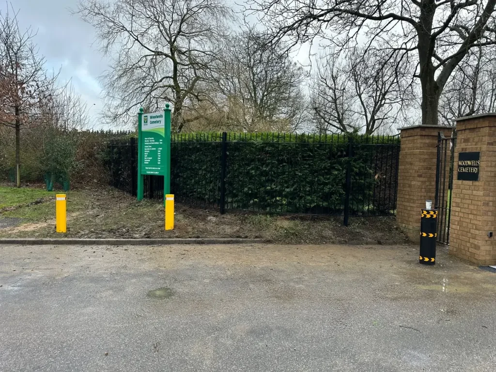 Black and yellow safety bollards protecting a paved site entrance