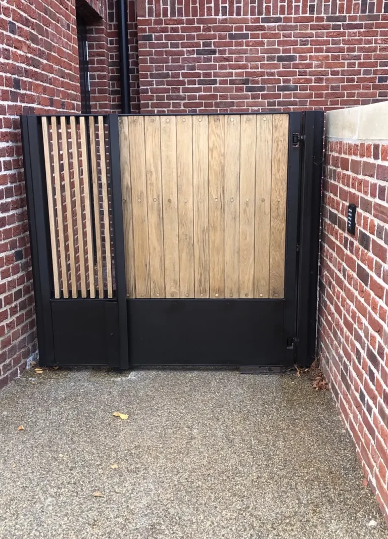 A timber-clad side gate in a brick surround on a gravel path