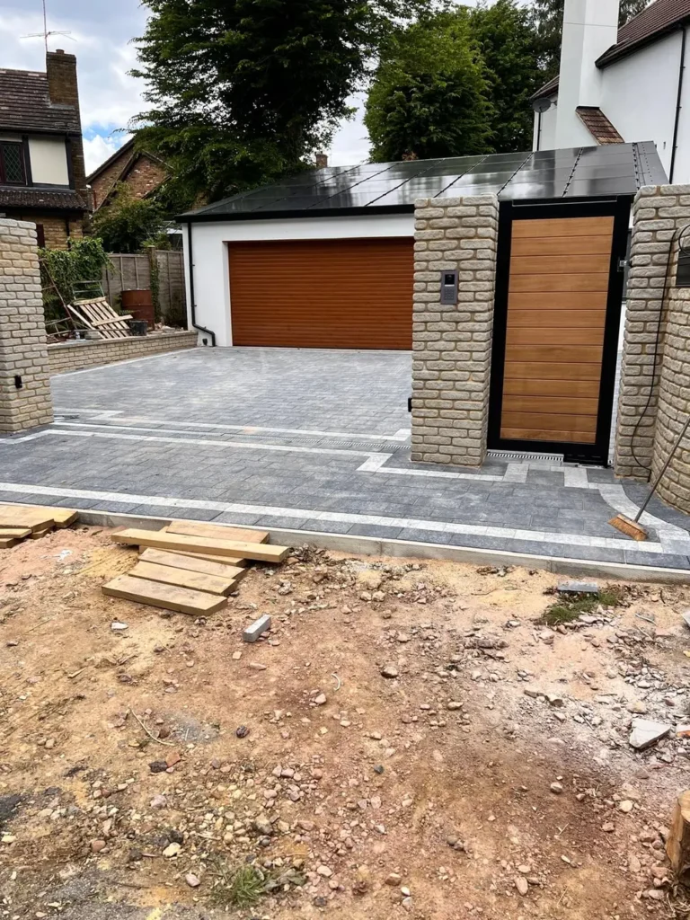 Timber driveway gates beside a garage on a gravel drive