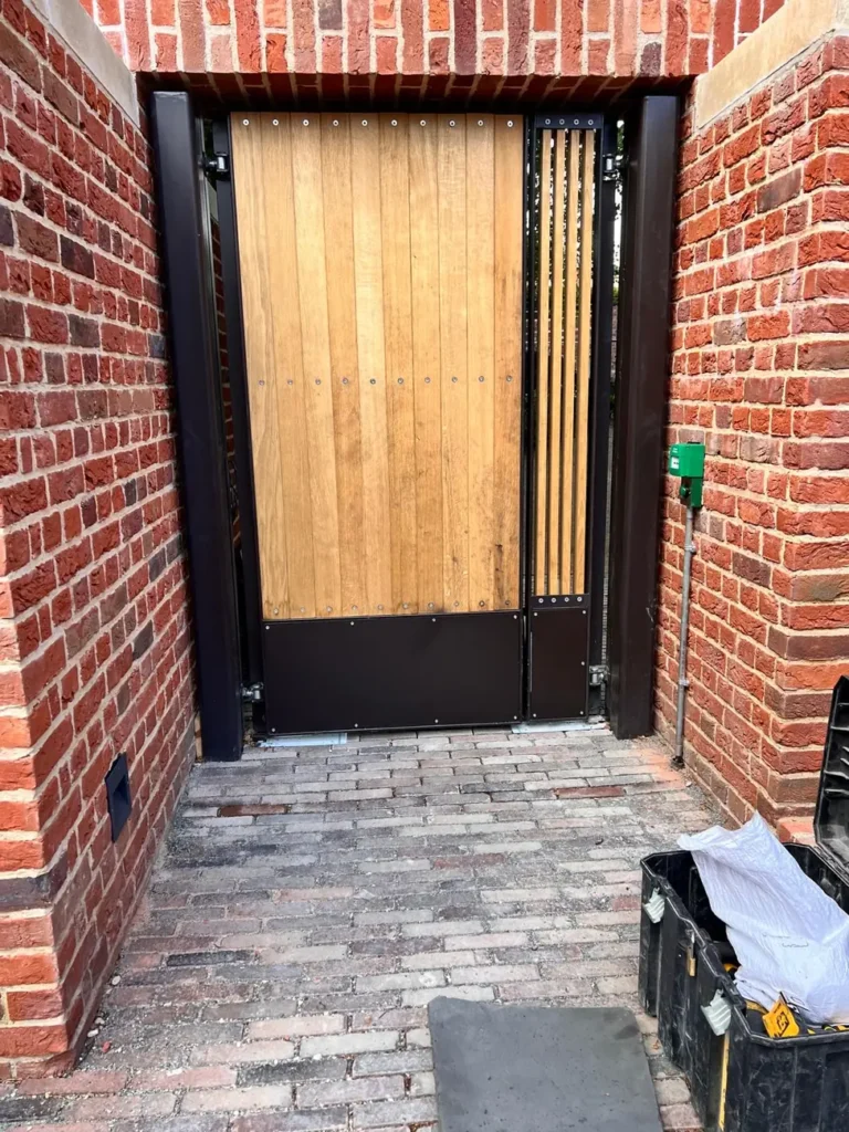 A timber pedestrian gate with keypad entry in a red-brick surround