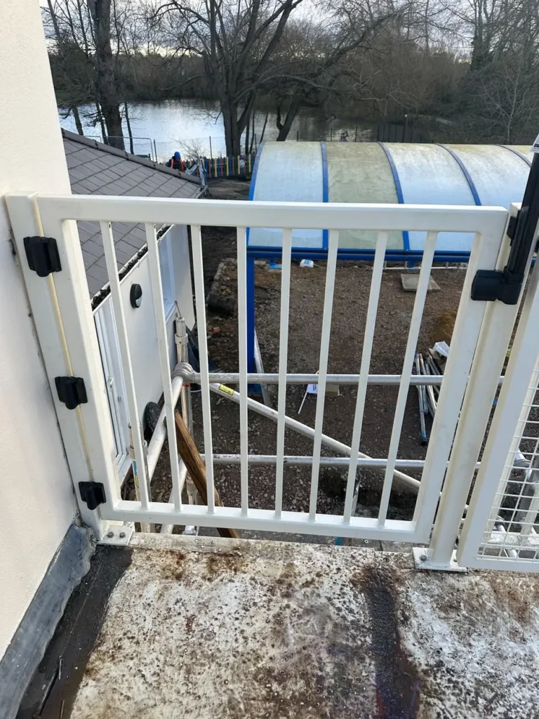 A white metal pedestrian gate on a waterside walkway