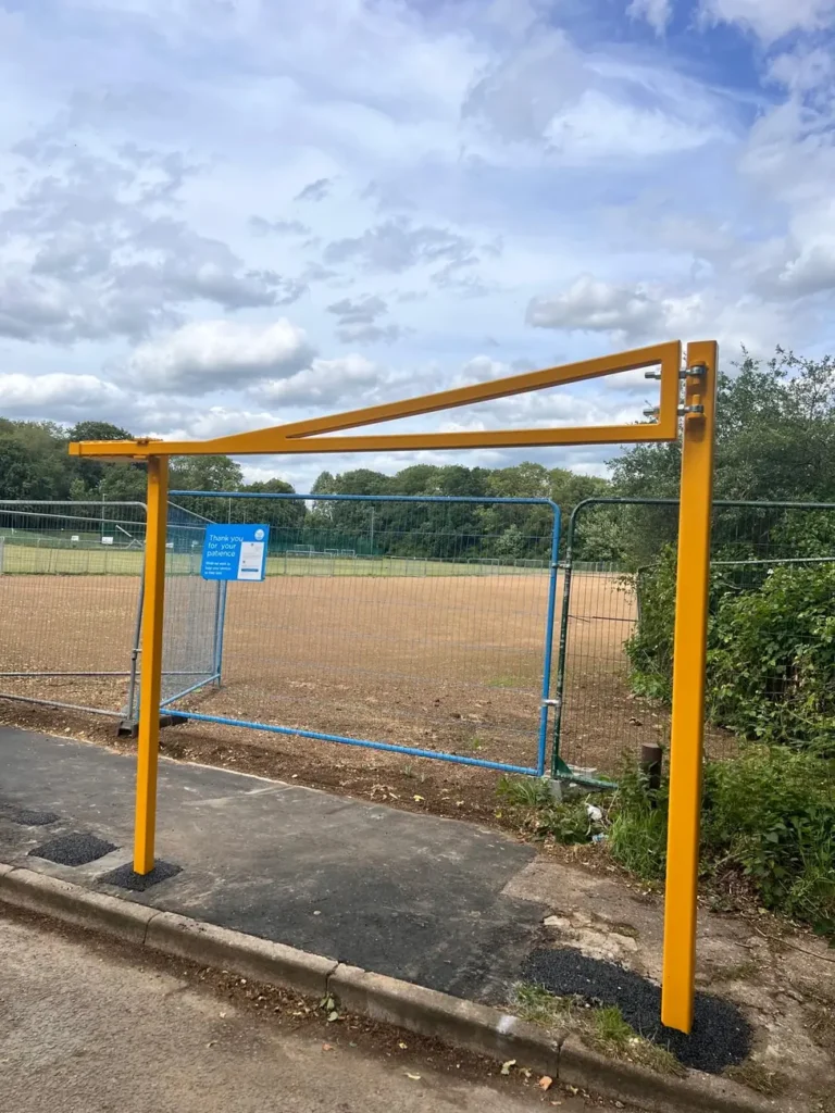 A yellow height restriction barrier at a field car park entrance