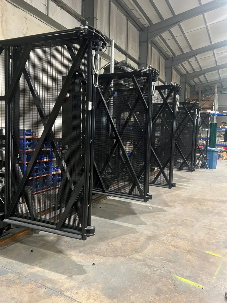 Black bi-folding speed gates with mesh infill, assembled on their towers
